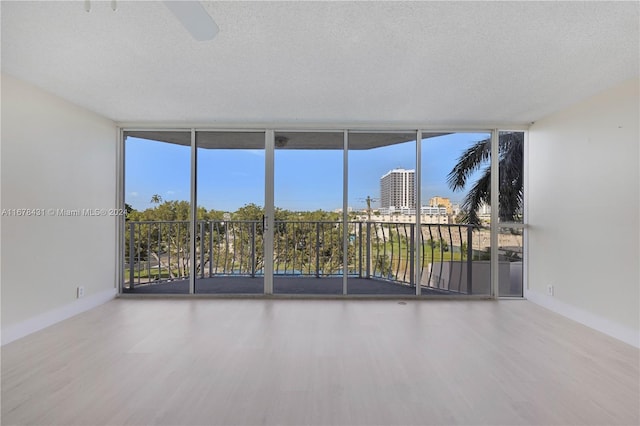 empty room featuring hardwood / wood-style floors, a wall of windows, and a textured ceiling