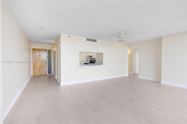 unfurnished living room with light hardwood / wood-style floors, a textured ceiling, and ceiling fan