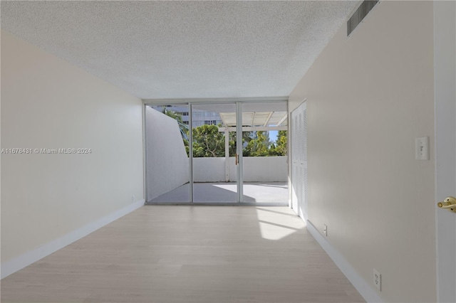 hall featuring floor to ceiling windows, a textured ceiling, and light wood-type flooring