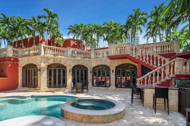 view of swimming pool with an in ground hot tub, a patio area, an outdoor bar, and french doors