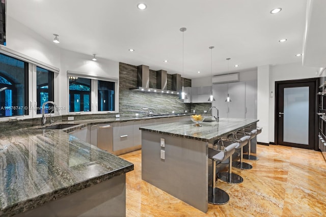 kitchen featuring a large island, dark stone counters, sink, and hanging light fixtures