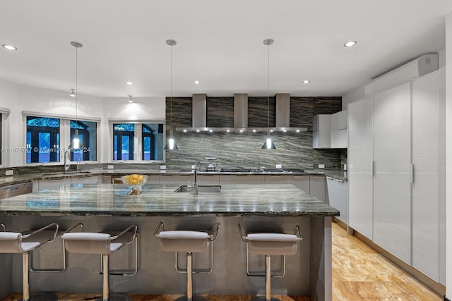 kitchen with white cabinetry, a spacious island, decorative light fixtures, and dark stone counters