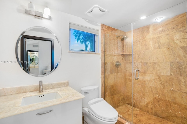 bathroom featuring vanity, a shower with shower door, and toilet