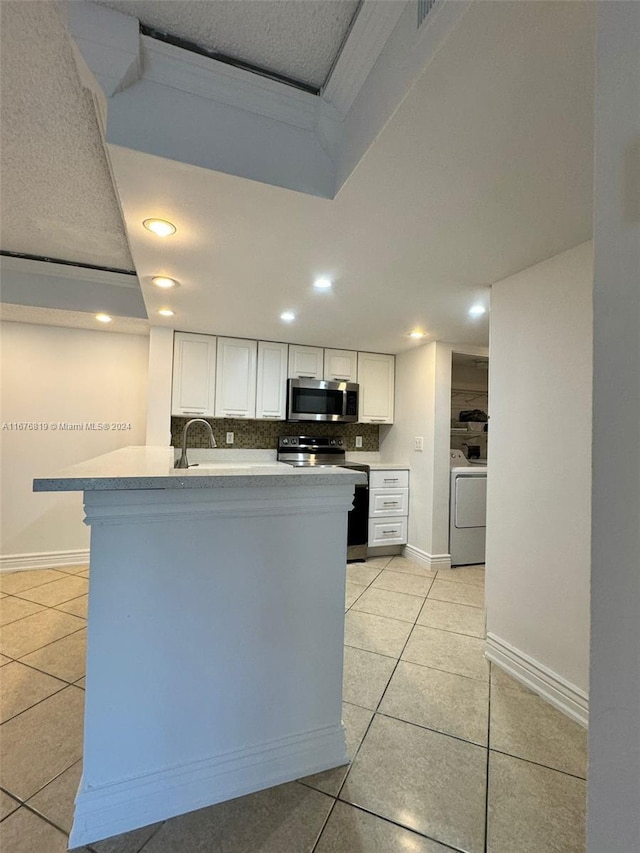 9200 W Atlantic Blvd Unit 1427, Coral Springs, FL 33071 - kitchen with stainless steel microwave, electric stove, washer / clothes dryer, light tile patterned floors, and white cabinetry