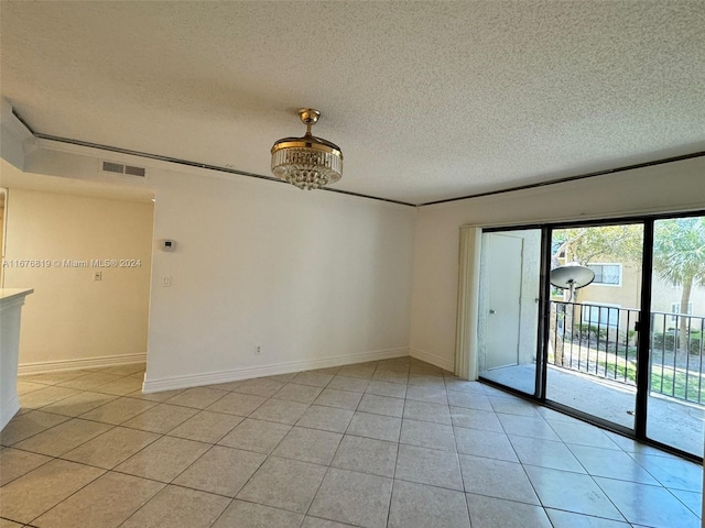 empty room with a textured ceiling and light tile patterned floors