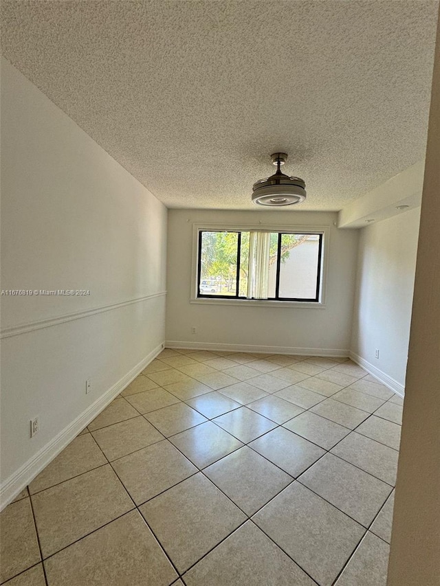 spare room featuring a textured ceiling and light tile patterned floors