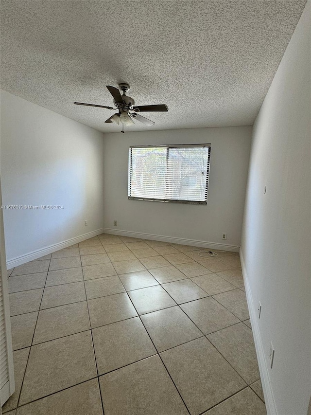 tiled spare room with a textured ceiling and ceiling fan