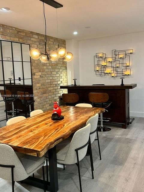 dining space with hardwood / wood-style floors and brick wall