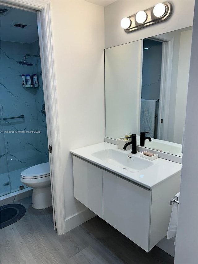 bathroom featuring vanity, hardwood / wood-style flooring, toilet, and walk in shower