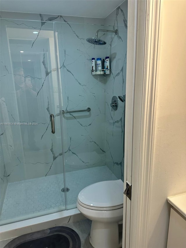 bathroom featuring vanity, toilet, and a shower with shower door