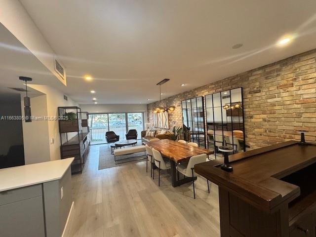 dining space with light hardwood / wood-style floors and brick wall