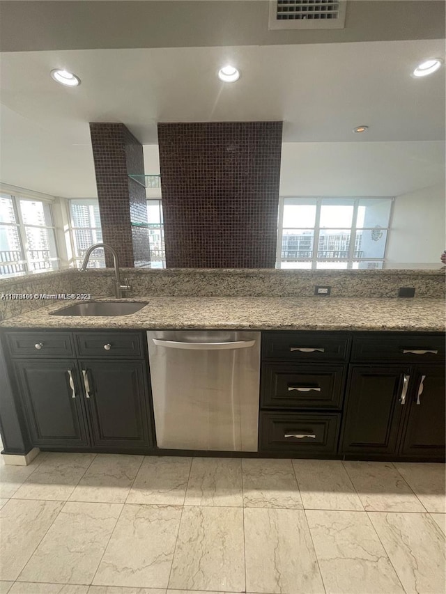 kitchen with stainless steel dishwasher, light stone countertops, and sink