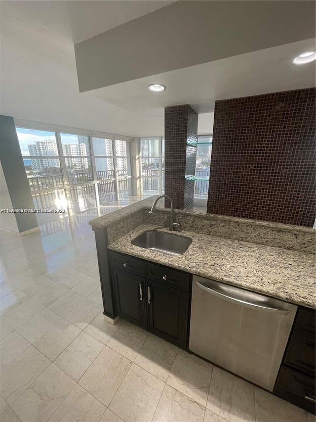 kitchen featuring dishwasher, light stone counters, and sink