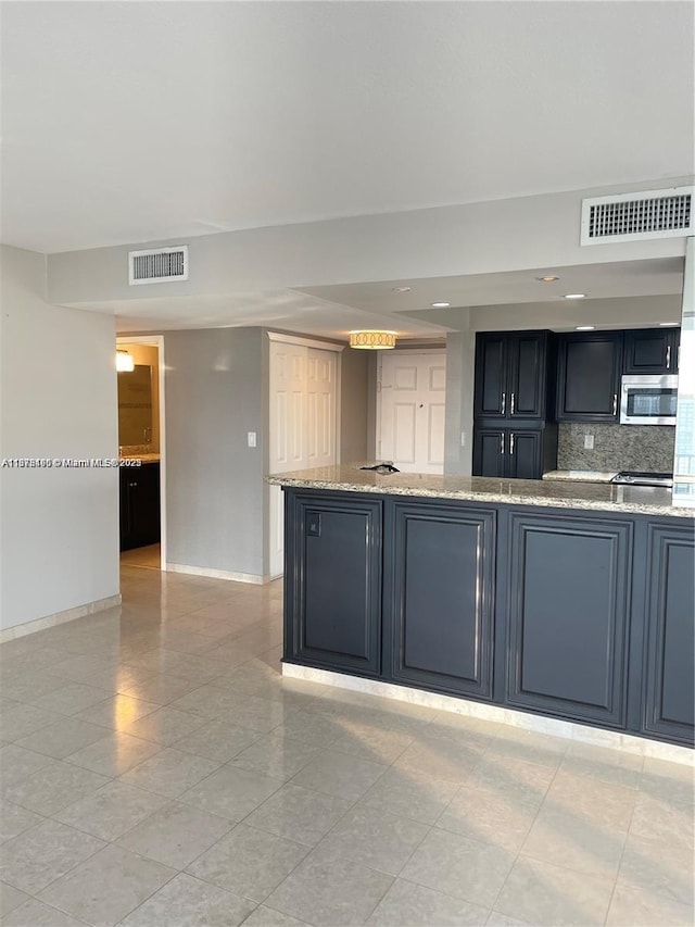 kitchen featuring light stone countertops, light tile patterned floors, and backsplash