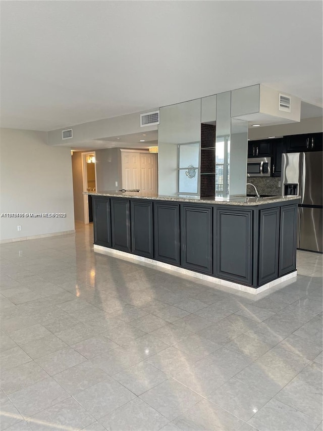 kitchen featuring a large island, decorative backsplash, light stone countertops, and stainless steel appliances