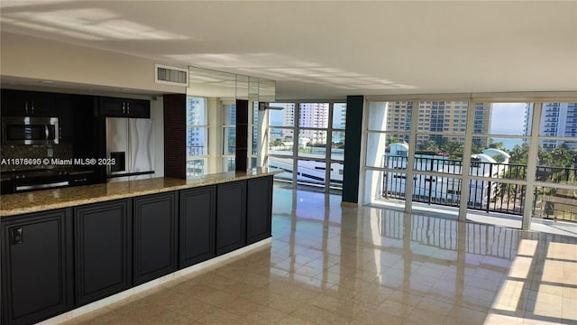 kitchen featuring light stone countertops, a wall of windows, and stainless steel appliances