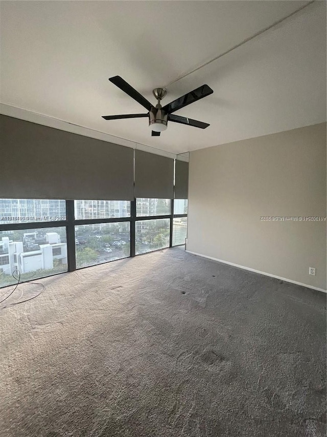 spare room featuring carpet, expansive windows, and ceiling fan