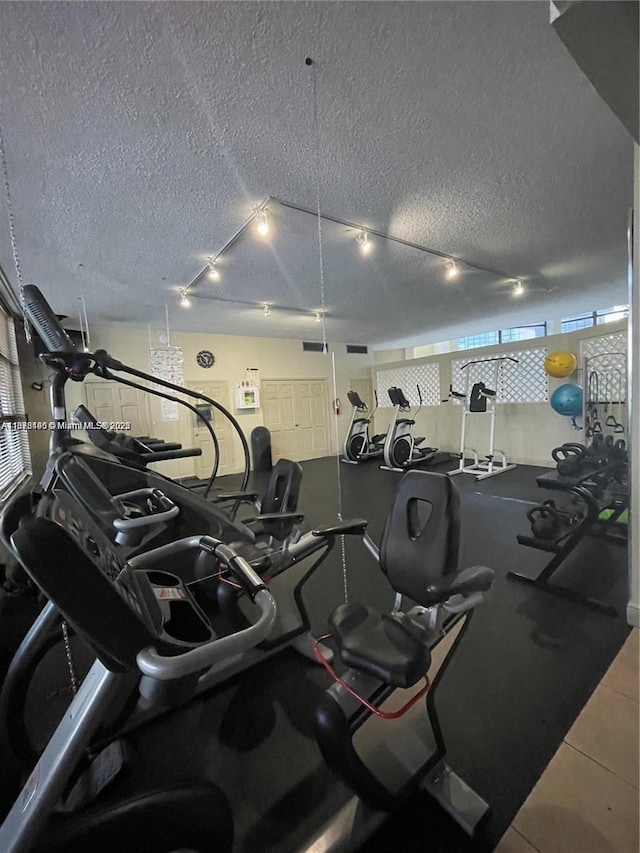 workout area featuring rail lighting and a textured ceiling