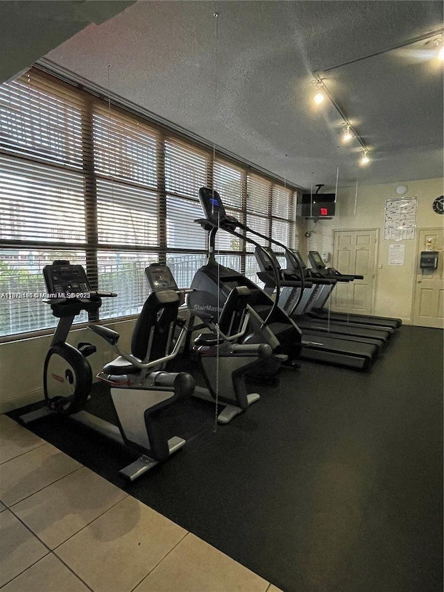 gym with tile patterned flooring, a textured ceiling, and track lighting