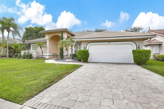 mediterranean / spanish-style home featuring a front yard and a garage