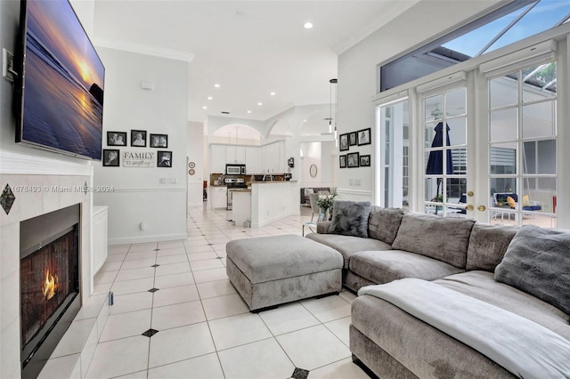 living room with crown molding, a tiled fireplace, and light tile patterned flooring