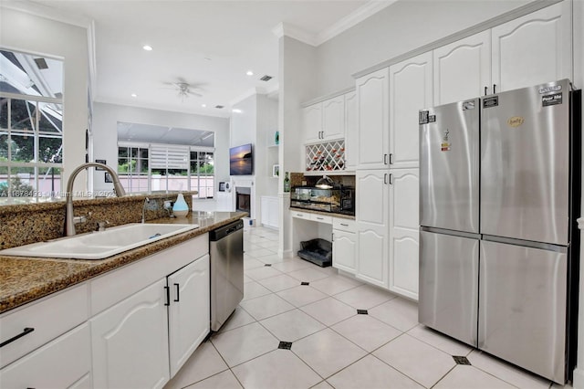 kitchen featuring sink, stainless steel appliances, dark stone counters, white cabinets, and ornamental molding