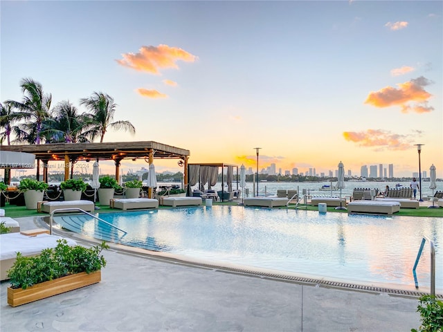 pool at dusk featuring a dock