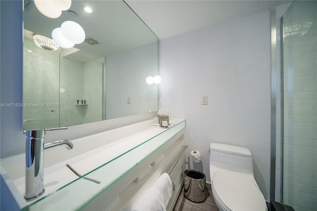 bathroom with vanity, toilet, and tiled shower