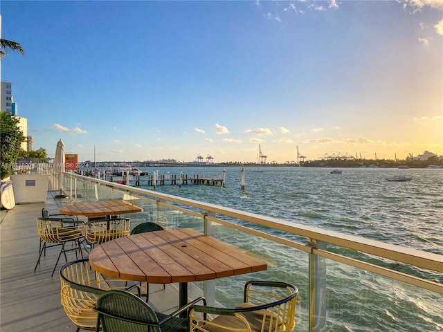 balcony at dusk featuring a water view