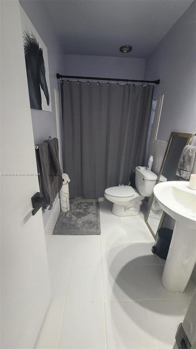 bathroom with toilet, walk in shower, and tile patterned floors