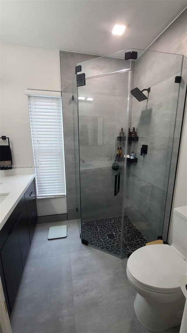 bathroom featuring toilet, a shower with shower door, and vanity