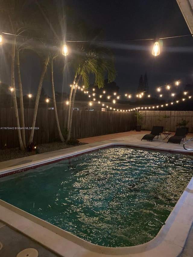 pool at twilight with a patio area