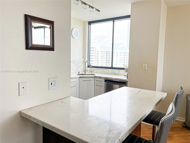 kitchen featuring kitchen peninsula, white cabinets, a breakfast bar area, stainless steel dishwasher, and sink