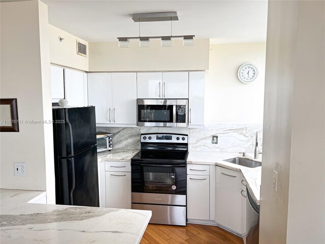 kitchen featuring backsplash, sink, appliances with stainless steel finishes, and white cabinets