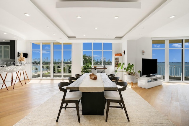 dining space featuring a raised ceiling, floor to ceiling windows, and wood finished floors