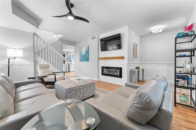 living room featuring light hardwood / wood-style flooring, a fireplace, and ceiling fan