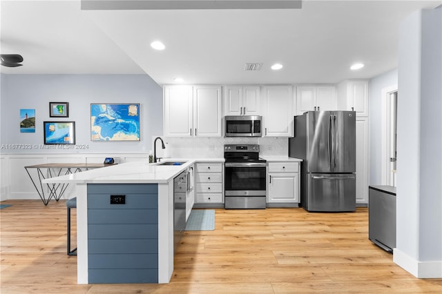 kitchen with light hardwood / wood-style flooring, white cabinetry, stainless steel appliances, and sink