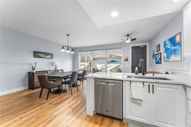 kitchen featuring hanging light fixtures, white cabinetry, light wood-type flooring, dishwasher, and sink