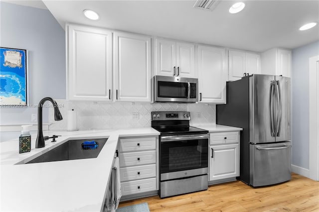 kitchen featuring sink, white cabinetry, stainless steel appliances, and light hardwood / wood-style floors