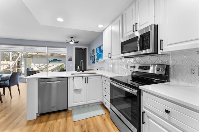 kitchen featuring appliances with stainless steel finishes, decorative backsplash, white cabinetry, and light wood-type flooring