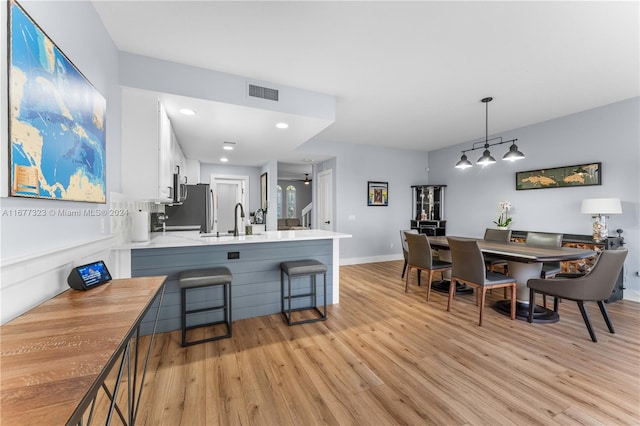 kitchen with a kitchen breakfast bar, white cabinetry, kitchen peninsula, and light hardwood / wood-style floors