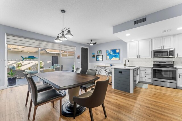 dining room featuring sink, ceiling fan, a textured ceiling, and light hardwood / wood-style flooring