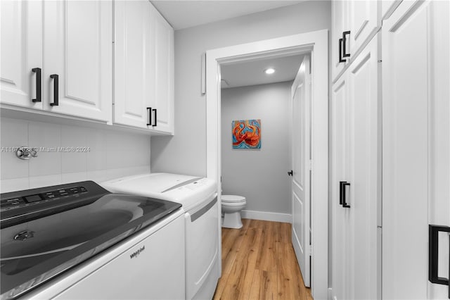 laundry room featuring independent washer and dryer, cabinets, and light hardwood / wood-style flooring