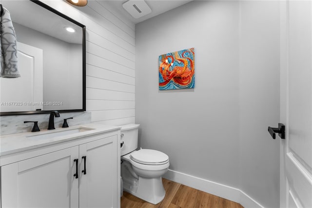 bathroom featuring vanity, hardwood / wood-style floors, toilet, and wood walls