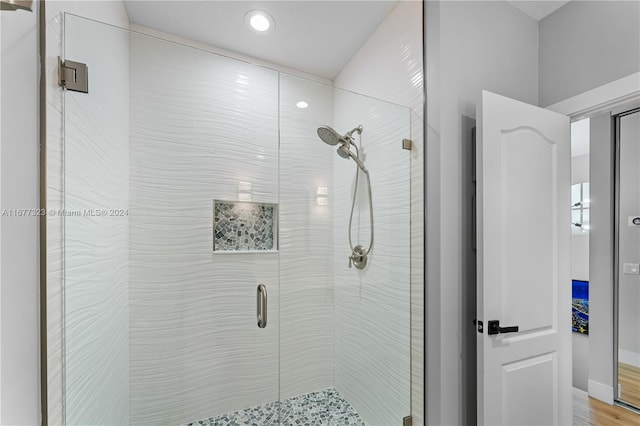 bathroom with a shower with door and hardwood / wood-style flooring