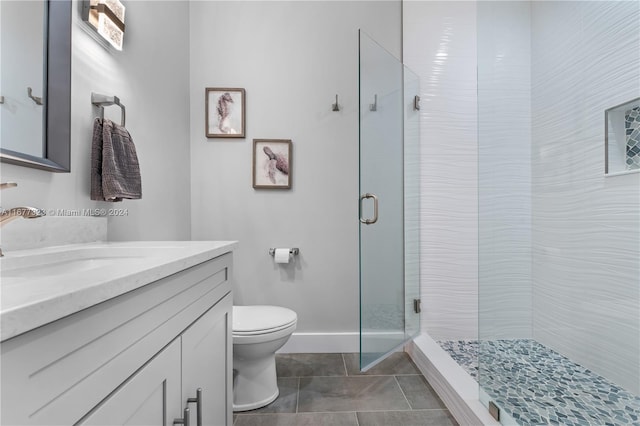 bathroom featuring vanity, toilet, tile patterned floors, and a shower with door