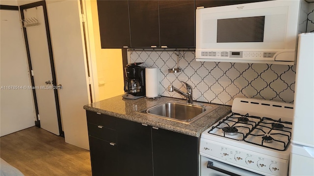 kitchen featuring white appliances, tasteful backsplash, sink, light wood-type flooring, and dark stone countertops