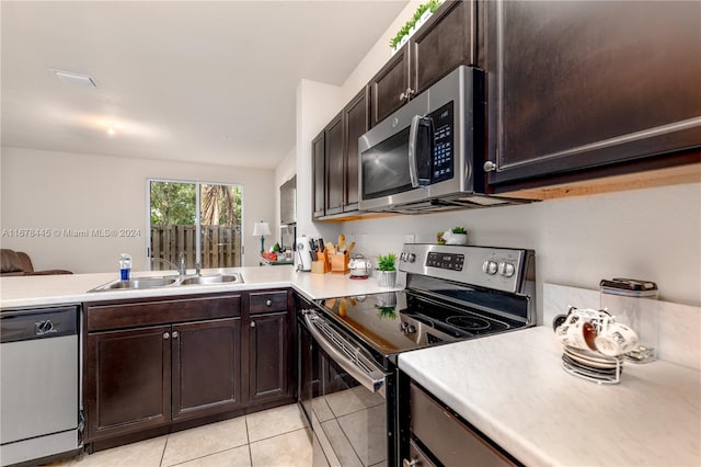 kitchen with sink, dark brown cabinets, kitchen peninsula, stainless steel appliances, and light tile patterned floors