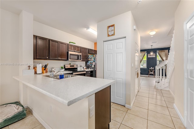 kitchen with kitchen peninsula, stainless steel appliances, sink, dark brown cabinetry, and light tile patterned floors