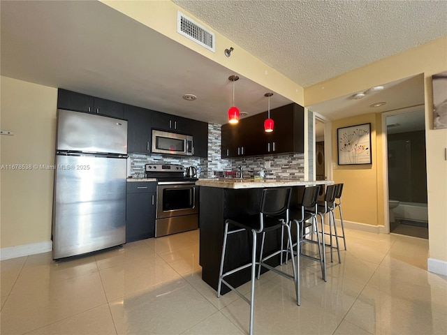 kitchen featuring a kitchen breakfast bar, light tile patterned flooring, visible vents, decorative backsplash, and appliances with stainless steel finishes